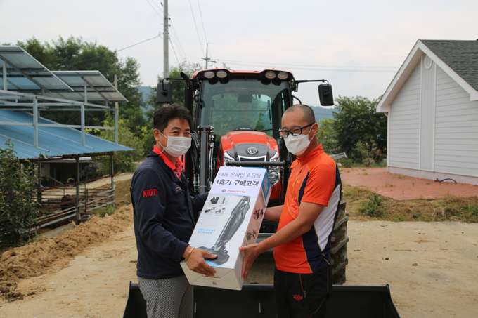 대동공업 경북지역본부 김현철 과장(왼쪽)이 '대동공업 쇼핑몰' 1호 계약 고객인 이현우씨(오른쪽)에게 계약한 PS1300트랙터 및 사은품을 전달하고 있다.
