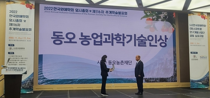 ㈜조비 이승연 사장이 한국원예학회 임시총회에서 '2022 동오 농업과학기술인상' 수상자인 이희재 서울대학교 교수(오른쪽)에게 상패를 수여하고 있다.