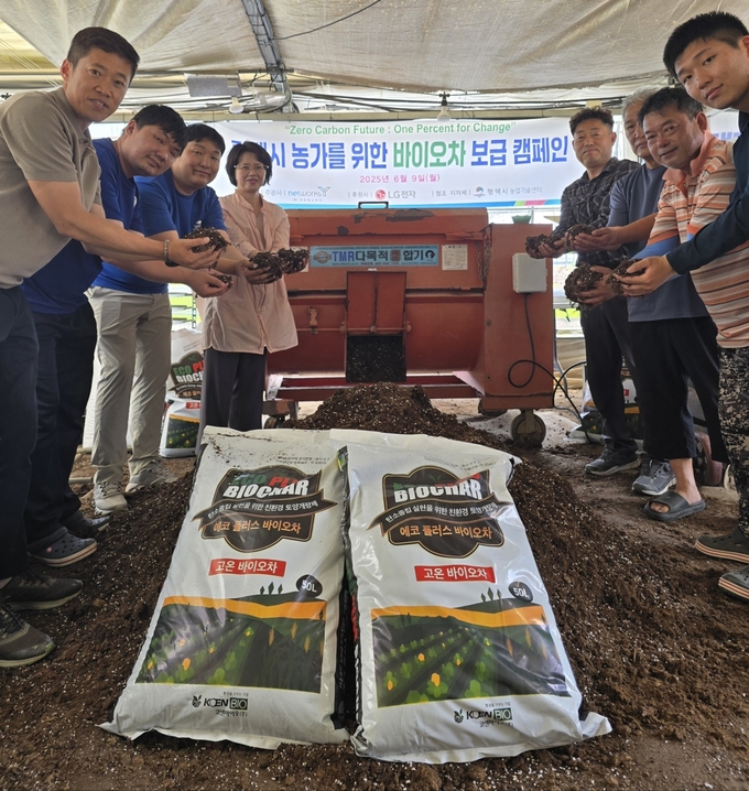 평택시농업기술센터 담당자 및 농민들이 에코 플러스 바이오차가 혼합된 토양을 들고 기념촬영을 하고 있다. (사진제공=㈜네트웍스와이)