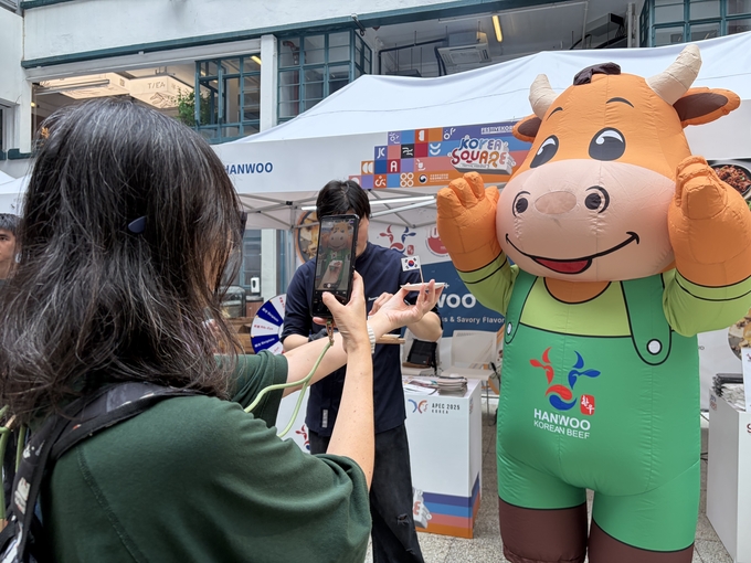 ‘2025 한국광장(Korea Square)’ 페스티벌 관람객이 전국한우협회 마스코트 앞에서 태극기와 함께 사진을 찍고 있다.